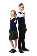 Cute girl and boy in school uniform showing thumb up gesture on white background