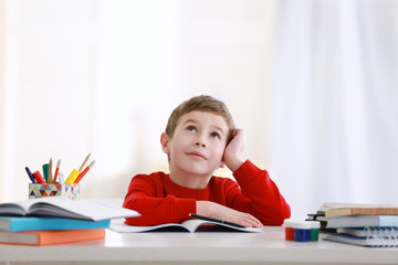 Schoolboy doing homework at table in room