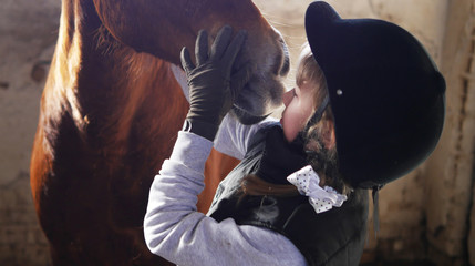 Girl stands near the horse. Girl hugging a horse.
