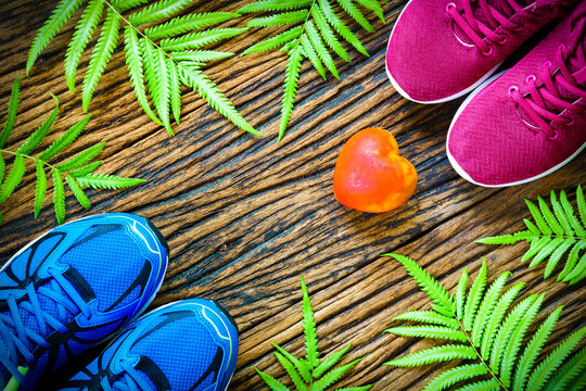Fitness, healthy and active lifestyles lover Concept, male and female sport shoes and pink dumbbells on wooden background. copy space for text. Top view