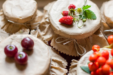 Fruit preserves and raw strawberries , cherries , rowans berries on a jars, organic meal and dessert concept