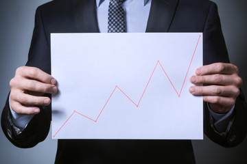 uptrend on the chart. a man in a business suit holding a sheet with the schedule of the uptrend.