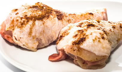 Two chicken legs with spices on a white plate, cooking concept