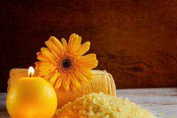 Spa yellow products setting. Sea salt ,towel and candles on dark wooden background