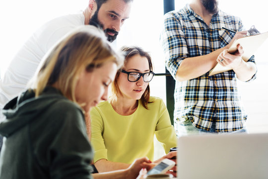 Young managers of the modern start up are discussing the business strategy for the next year in the modern and bright office. Hipsters are sitting with the electronic devices during meeting.