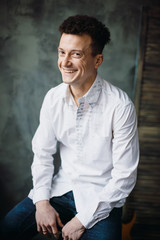 Brunette man smiles broad sitting on bar chair