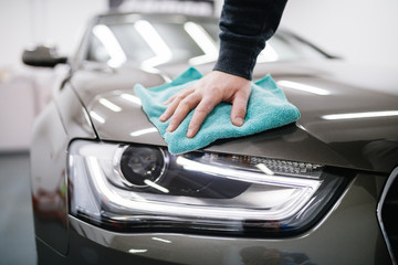 A man cleaning car with microfiber cloth, car detailing (or valeting) concept. Selective focus. 