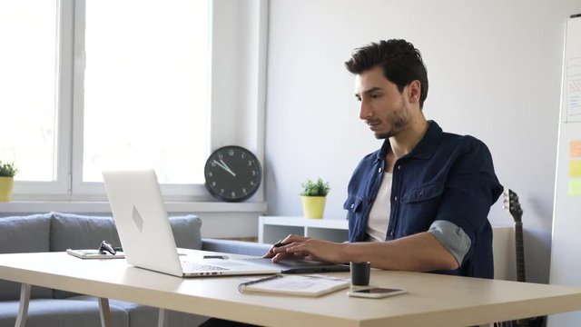 Freelance graphic designer sketching on tablet, working from home office.