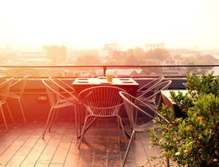 Dinning table set at rooftop looking down city view at colorful sunset