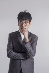 Young handsome man in gray suit and glasses looking at copy-space thinking or dreaming with gray background