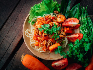  spaghetti chicken and shrimp on tomato sauce on wooden background