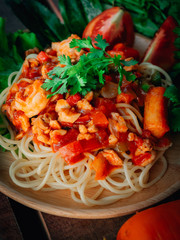  spaghetti chicken and shrimp on tomato sauce on wooden background