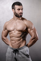 Fototapeta na wymiar Brutal strong bodybuilder man posing in studio on grey background.