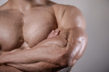 Naklejka premium Brutal strong bodybuilder man posing in studio on grey background.