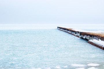 Frozen sea in winter and snow on the concrete pier