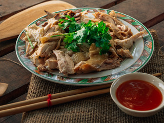 Vintage style Thai traditional food chicken boiled with sauce and spicy chili sauce on top with wooden background wallpaper