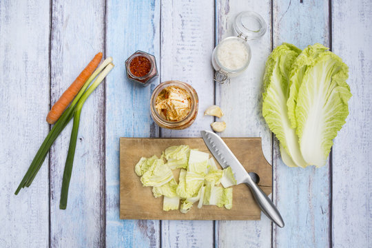 Glass of Kimchi, ingredients, wooden board and kitchen knife on wood