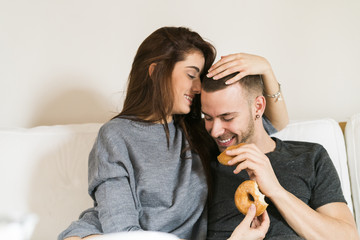 Amorous couple sitting on couch, having breakfast