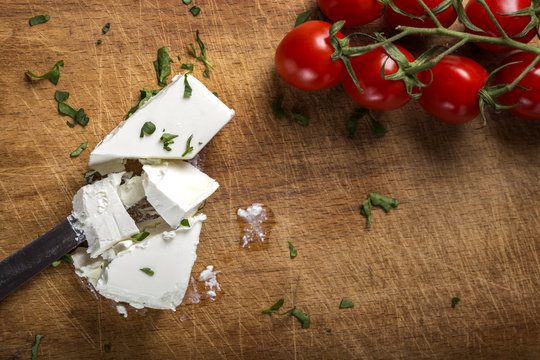 Feta cheese with knife and bunch of cherry tomatoes