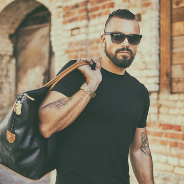 Handsome Man With Beard Wearing Sunglasses And Holding Black Bag