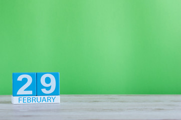 February 29th. Cube calendar for february 29 on wooden workplace with with green background and empty space For text. Leap year, intercalary day