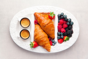Summer breakfast on a tray. Fresh ripe berries, pastries and two cups of coffee espresso
