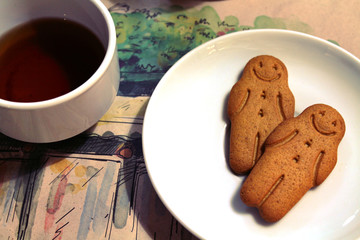 Black tea and gingerbread men cookies in a white bowl in a cafe