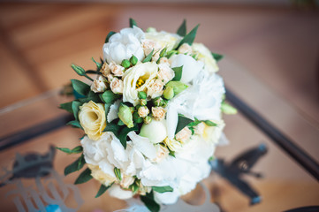 wedding Bouquet of white roses with a blue ribbon on the glass table in a room