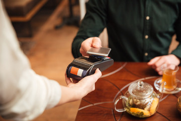 Cropped image of amazing young man pays the order