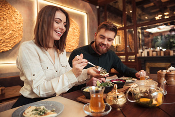 Young loving couple sitting in cafe and eating.