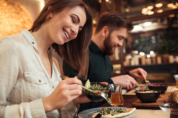 Attractive young loving couple sitting in cafe and eating.