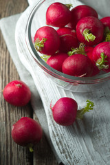 Red radish in a glass bowl on a wooden stand