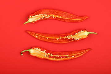 Three cut hot chili peppers on red background