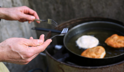 cook frying large pancakes in a pan of hot oil in a street food