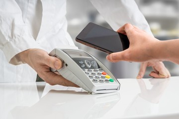 Customer is paying with smartphone using NFC technology in pharmacy.