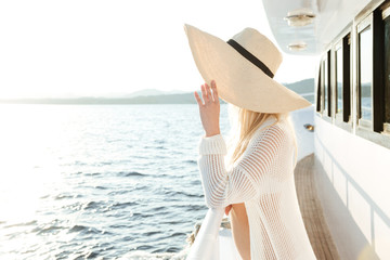 Attractive beautiful woman wearing hat posing on the yacht - obrazy, fototapety, plakaty