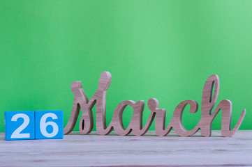 March 26th. Day 26 of month, daily wooden calendar on table and green background. Spring time,...