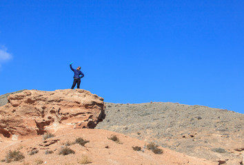 Happy woman standing on the top of the hill with raised hands  and enjoy the view 

