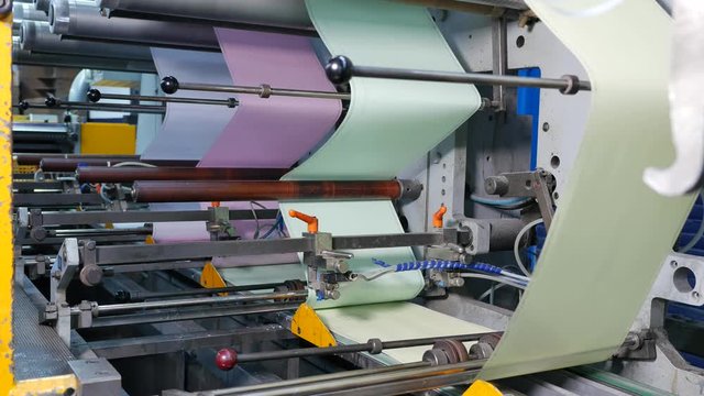 Blue, pink, green and yellow paper on the assembly line of an envelope factory