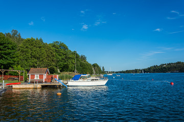 En brygga ute i Stockholms skärgård med en vit båt förtöjd