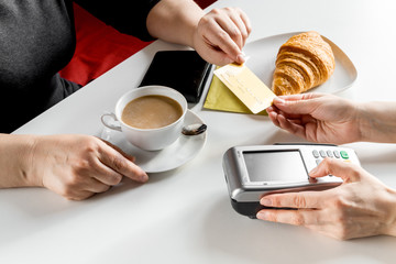 Croissant and coffee on white table payment by card in cafe