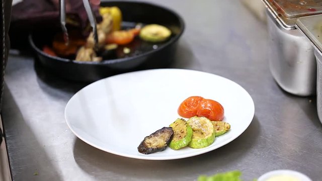grilled vegetables spread with forceps from the frying pan onto a plate
