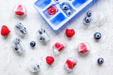 Obraz na płótnie Canvas blueberry and raspberry in ice tray on stone background top view