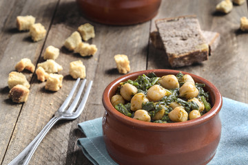 Chickpea and spinach stew on rustic wooden background. Spanish cuisine.