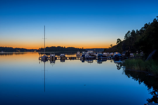 Vy över vattnet och en båtbrygga vid Ålstäket en sommarnatt