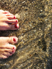 Feet in water on the pebble shore beach photo