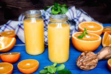 healthy orange cocktail with mint leaves in bottle on kitchen background