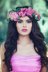 Naklejka premium Perfect Model Woman with Summer Pink Flowers Outdoors. Beautiful Young Woman with Long Curly Hair