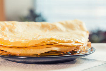 Honey is poured on a stack of pancakes. Sunlight. Close up.