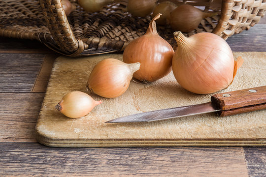 Onions on the old wooden board in the kitchen. Healthy eating and lifestyle.